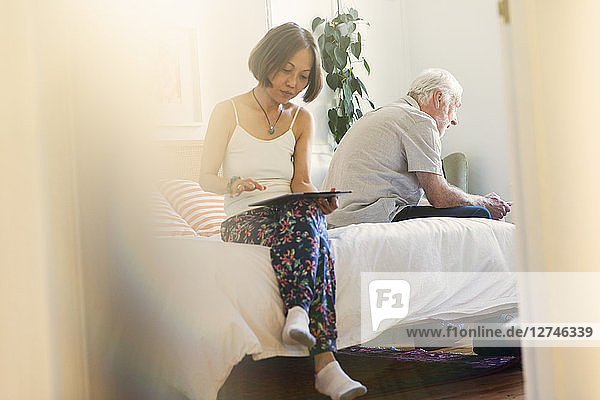 Senior couple using digital tablets in bedroom