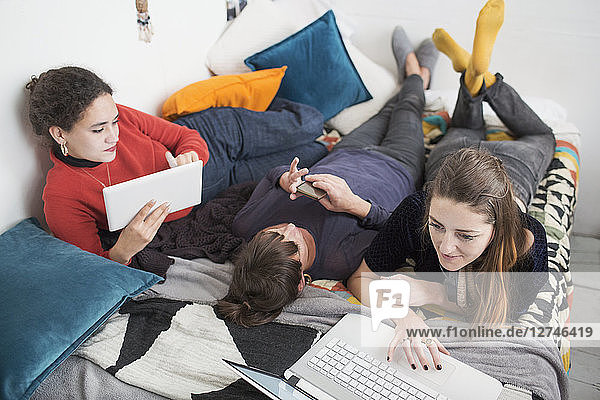 Young women college student roommates studying on bed
