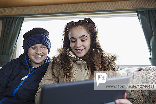 Bruder und Schwester im Teenageralter benutzen ein digitales Tablet im Wohnmobil