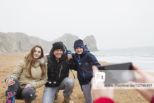 Happy family posing for photograph on snowy winter beach