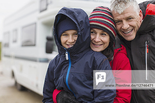Porträt einer liebevollen Familie in warmer Kleidung,  die sich außerhalb des Wohnmobils umarmt