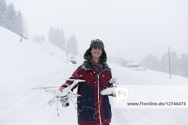 Portrait smiling teenage boy with drone in snowy landscape