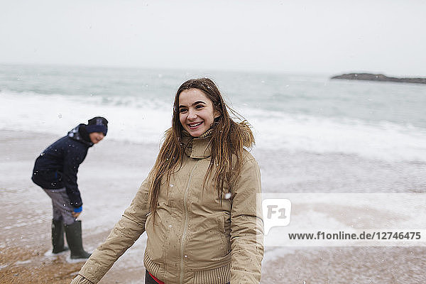 Lächelndes Teenager-Mädchen am winterlichen Meeresstrand
