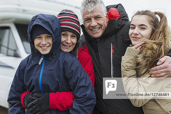 Porträt liebevolle glückliche Familie in warmer Kleidung vor Wohnmobil