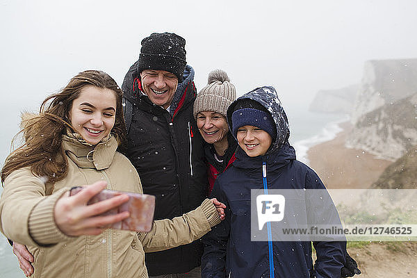 Schneefall über einer Familie  die ein Selfie mit einem Fotohandy macht