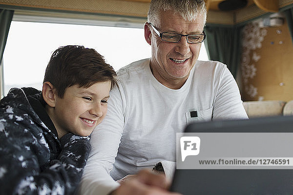 Vater und Sohn benutzen digitales Tablet im Wohnmobil