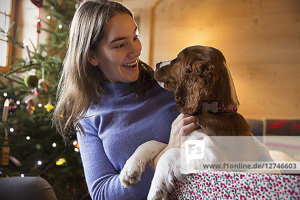 Teenage girl petting dog in Christmas gift box