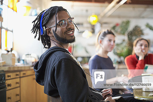 Portrait smiling young man with headphones at kitchen table