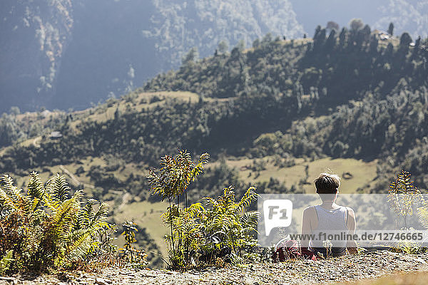 Weibliche Wanderin ruht sich aus und genießt die sonnige Aussicht  Supi Bageshwar  Uttarakhand  Indische Himalaya-Ausläufer