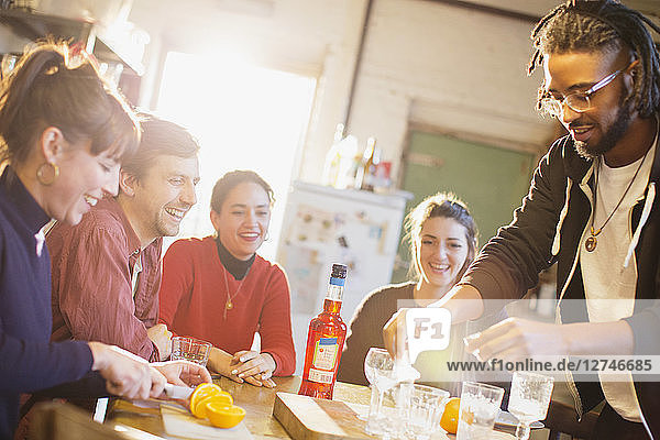 Young adult friends making cocktails at kitchen table