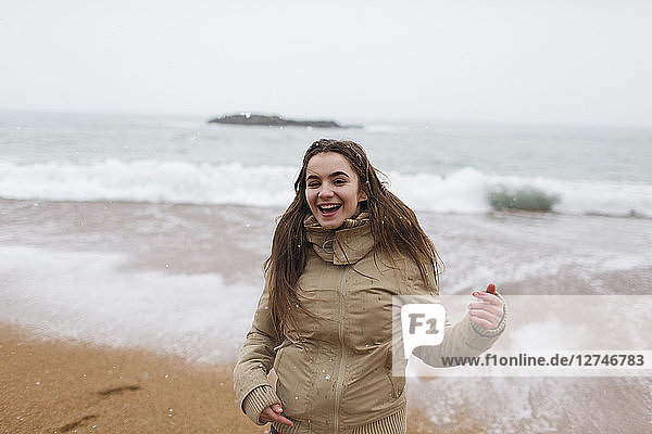Portrait happy  carefree teenage girl on snowy winter beach