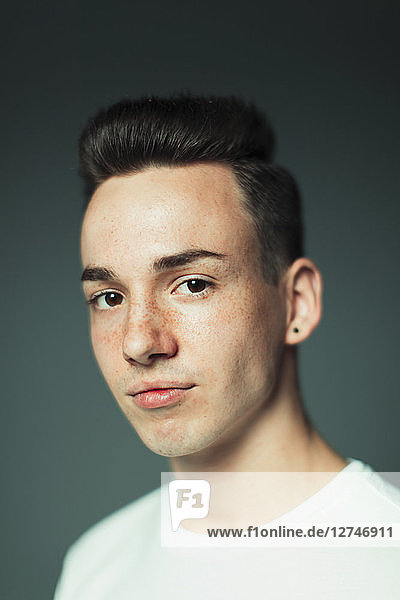 Portrait confident teenage boy with freckles and earring