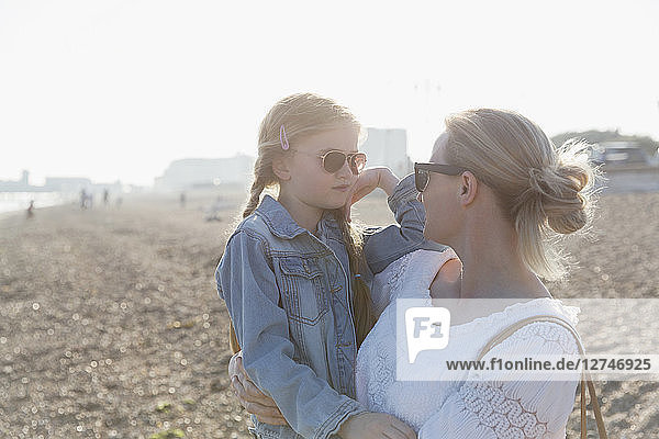 Mother and daughter wearing sunglasses on sunny beach