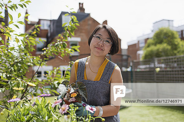 Portrait smiling woman gardening in sunny yard