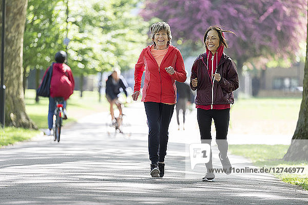 Active senior women friends jogging in park