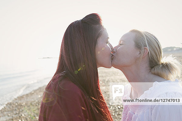 Affectionate lesbian couple kissing on sunny beach