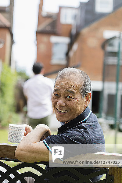 Portrait smiling senior man drinking tea in yard