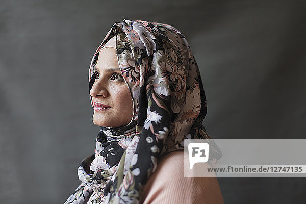 Serene  thoughtful woman wearing floral hijab  looking away