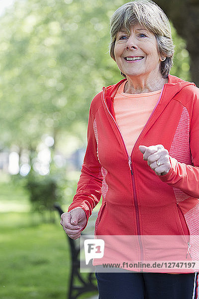 Smiling active senior woman running in park