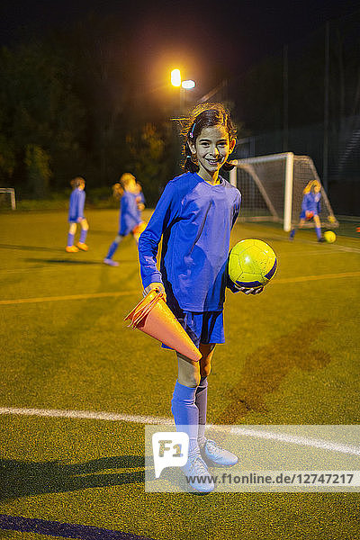 Porträt selbstbewusstes Mädchen Fußballspieler auf Feld bei Nacht
