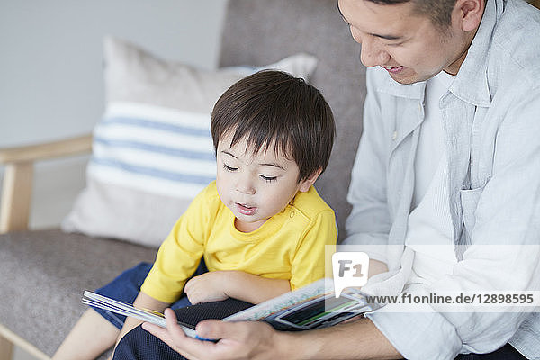 Japanese father and kid reading on the sofa
