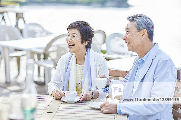 Japanese senior couple having a drink by the sea