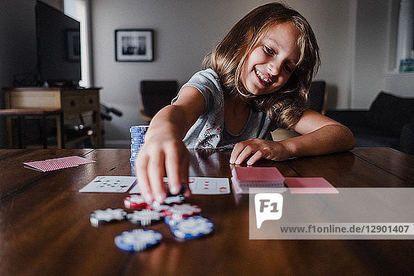 Mädchen spielen Karten am Tisch  platzieren Glücksspielchips