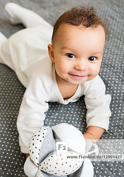 Baby boy lying on bed holding soft toy  portrait