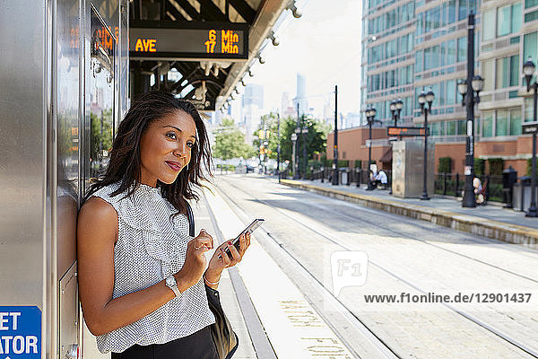 Businesswoman using cellphone by ticket machine