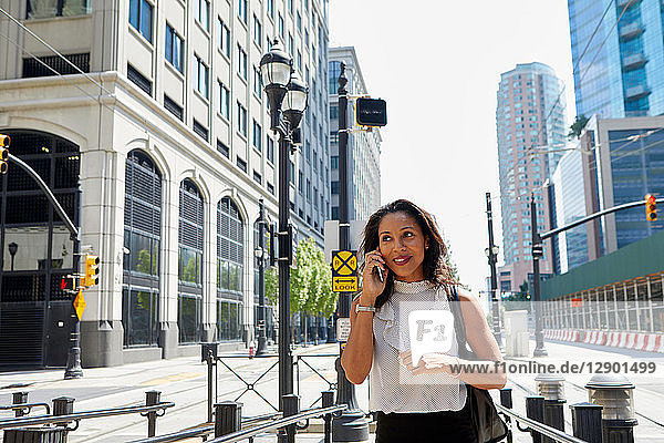 Businesswoman using cellphone by barriers
