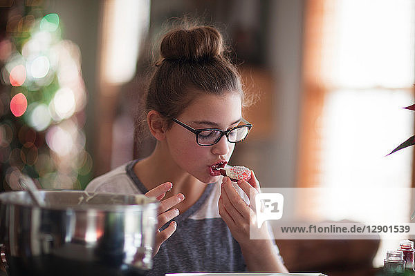 Girl eating her homemade christmas cookie at kitchen counter