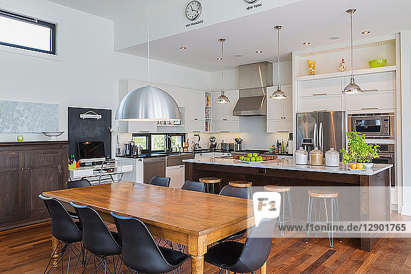 Open plan kitchen dining area with antique table marble top kitchen island in luxurious modern cube style house interior