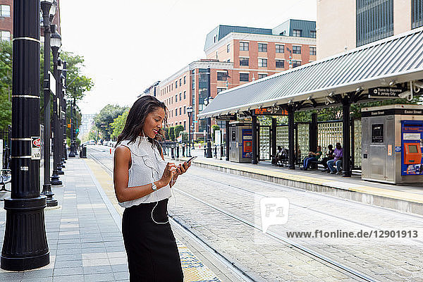 Businesswoman using cellphone in light rail station
