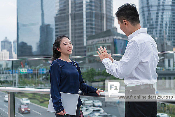 Junge Geschäftsfrau und Mann unterhalten sich auf dem Balkon im Finanzbezirk der Stadt  Shanghai  China