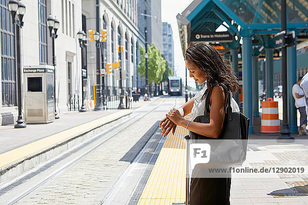Geschäftsfrau kontrolliert Zeit bei Stadtbahnlinie