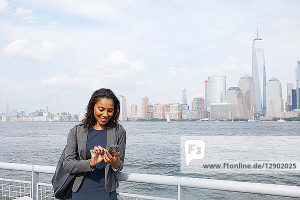 Geschäftsfrau telefoniert mit ihrem Handy  im Hintergrund die Skyline von New York City