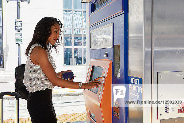 Geschäftsfrau kauft Zugfahrkarte am Automaten