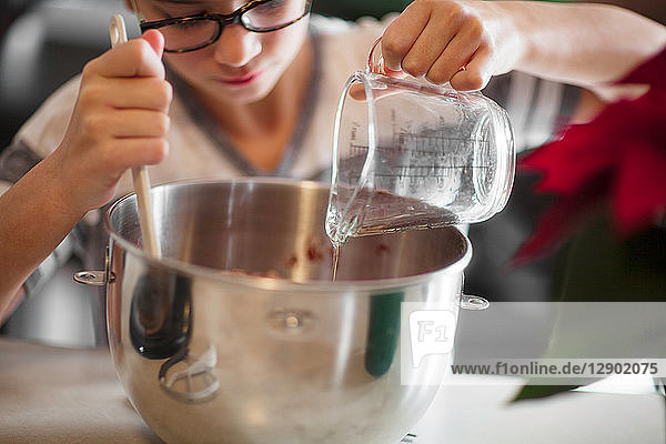 Girl pouring egg white into mixing bowl for christmas cookies at kitchen counter  close up