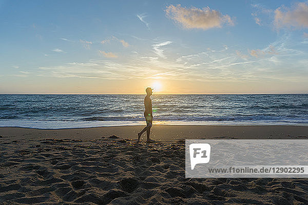 Mann geht bei Sonnenuntergang am Strand spazieren