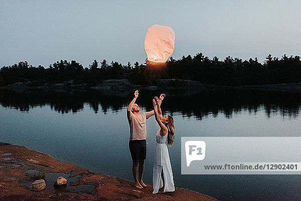 Couple releasing sky lanterns by lake  Algonquin Park  Canada