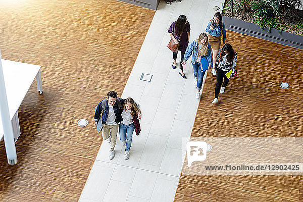 Männliche und weibliche Universitätsstudenten beim Gehen und Sprechen in der Universitätslobby  Hochwinkelansicht