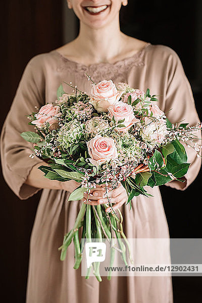 Frau hält Blumenstrauss aus frischen zartrosa Rosen