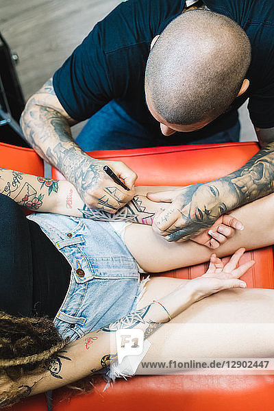 Tattooist drawing on arm of customer