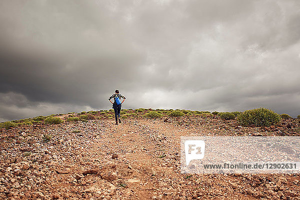 Woman hiking up hill on dirt track  rear view  Las Palmas  Gran Canaria  Canary Islands  Spain