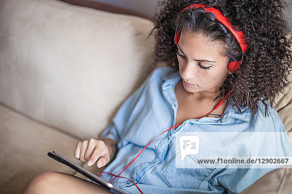 Frau hört zu Hause Musik auf digitalem Tablet