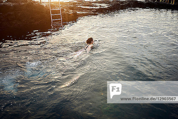 Frau schwimmt bei Sonnenuntergang im Küstenbecken  Las Palmas  Gran Canaria  Kanarische Inseln  Spanien