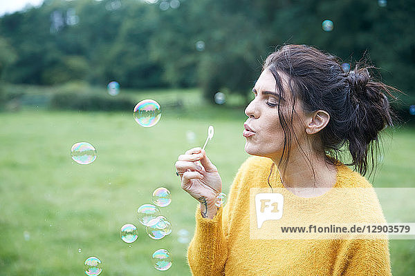 Frau spielt mit Seifenblasen auf dem Feld