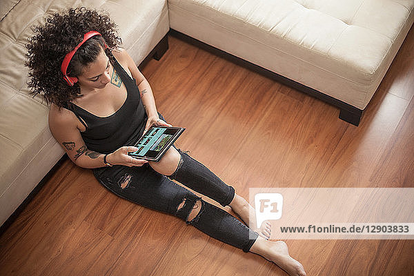 Frau hört zu Hause Musik auf einem digitalen Tablet