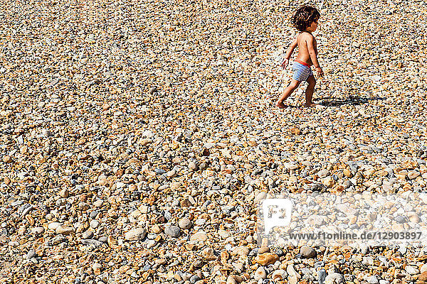 Toddler walking on pebble beach