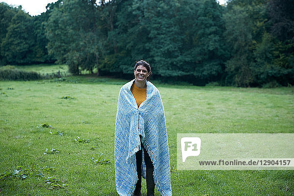 Mittelgroße erwachsene Frau im ländlichen Feld stehend  in eine Decke gewickelt  Ganzfigur